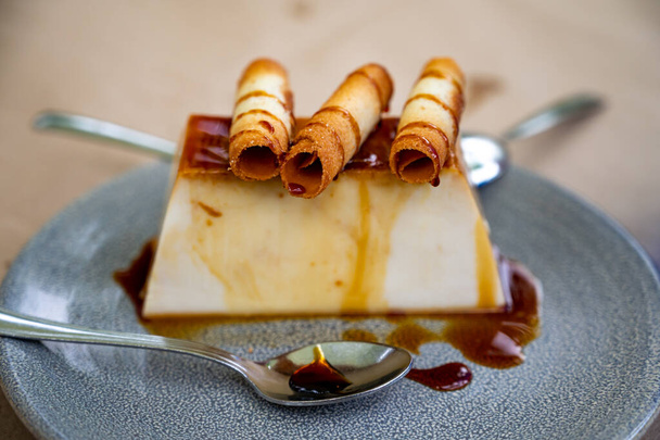 Солодкий десерт, чізкейк або флан, поданий з карамельною заваркою та вафельками, крупним планом
 - Фото, зображення