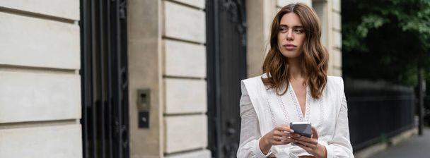 Traveler in blouse using mobile phone on urban street in Paris, banner  - 写真・画像