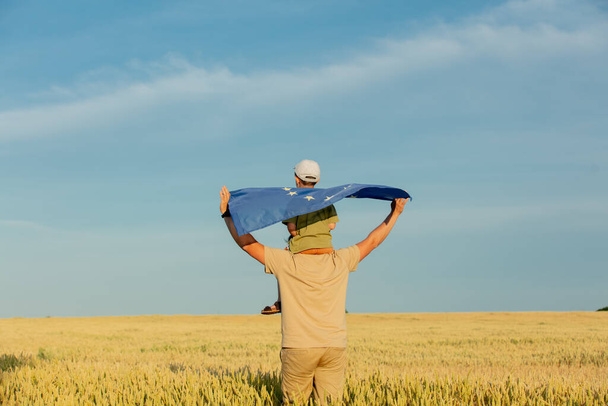 Отец с сыном и флагом ЕС на пшеничном поле - Фото, изображение