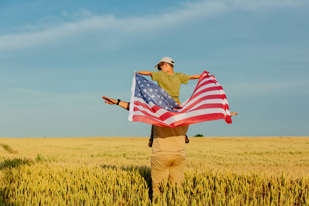 Père avec son fils et drapeau américain sur le champ de blé - Photo, image