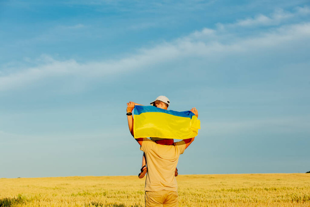 小麦畑に息子とウクライナの旗を持つ父 - 写真・画像