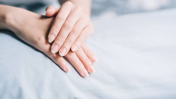 Die Hände oder Nägel der Frau werden auf ein hellblaues Tuch gelegt. Gesundheitskonzept für Nagel. - Foto, Bild