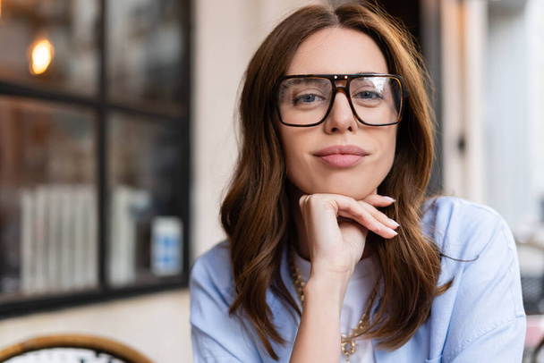 Brunette woman in eyeglasses looking at camera outdoors in France  - Photo, image
