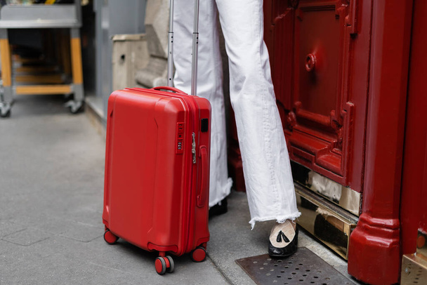 Cropped view of suitcase near traveler on urban street in Paris  - Foto, afbeelding