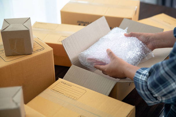 Closeup view of female online store small business owner seller entrepreneur packing package post shipping box preparing delivery parcel. - Photo, Image