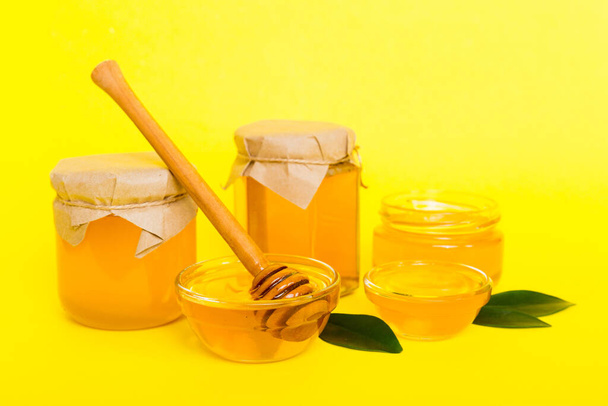 Honey in jar with leaves and honey dipper on colored background top view with copy text. - Photo, Image