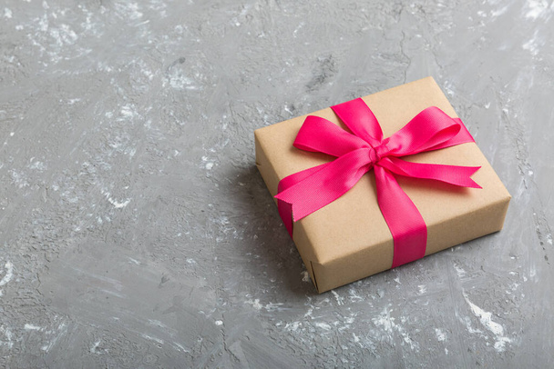 Τυλιγμένα Χριστούγεννα ή άλλο χριστουγεννιάτικο χειροποίητο δώρο σε χαρτί χειροτεχνίας με χρωματιστή κορδέλα. Παρόν κουτί, διακόσμηση του δώρου στο τραπέζι, πάνω άποψη με χώρο αντίγραφο. - Φωτογραφία, εικόνα