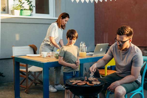 family of three preparing barbecue in home backyard - Foto, Bild