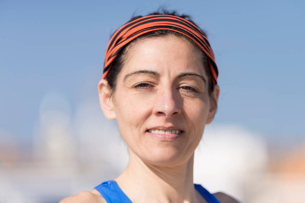 Headshot Close-up portret van een casual runner vrouw glimlachend, Authentieke mensen, alleen buiten op het zomerstrand, kijkende camera, lachend vriendelijk, openhartige foto 's, zonsondergang - Foto, afbeelding