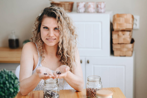 Femme au foyer trie les haricots dans la cuisine. Curly Woman tient des haricots dans ses mains. Nourriture végétarienne. Protéines végétales. - Photo, image
