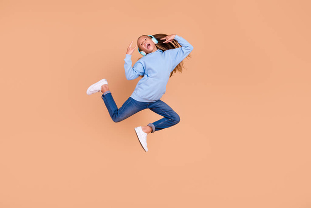 Full length portrait of childish carefree person jump hands fingers show rock horns symbol isolated on beige color background. - Foto, Bild