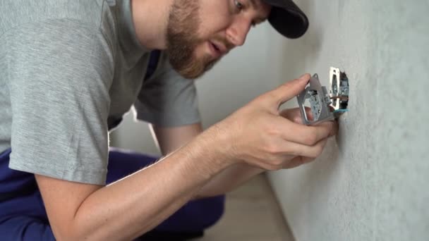 Homem eletricista em tomadas elétricas de montagem uniforme na parede branca dentro de casa, substituindo soquete no quarto - Filmagem, Vídeo