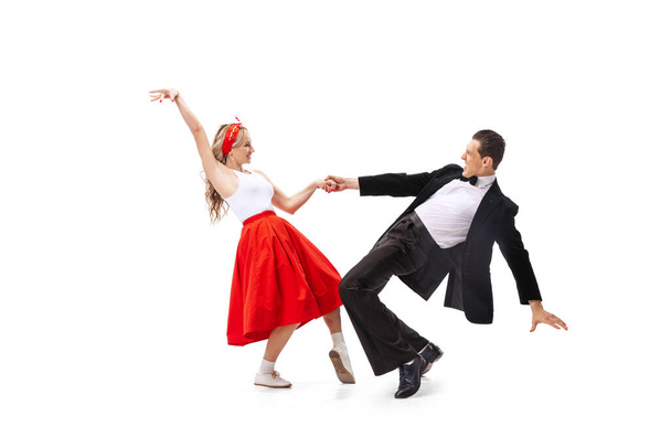 Coppia espressiva di ballerini in abiti vintage in stile retrò che ballano danza sociale isolata su sfondo bianco. Tradizioni senza tempo, anni '60, anni' 70 stile moda americana. I ballerini sembrano eccitati - Foto, immagini