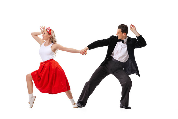 Music and dance. Astonished young man and woman in retro style outfits dancing lindy hop isolated on white background. Timeless traditions, 60s ,70s american fashion style. Emotions, expressions - Fotó, kép