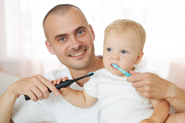 Father teaching baby boy brushing teeth. The concept of oral hygiene from the first tooth - Foto, immagini