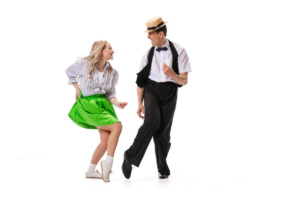 Music and dance. Astonished young man and woman in retro style outfits dancing lindy hop isolated on white background. Timeless traditions, 60s ,70s american fashion style. Emotions, expressions - 写真・画像