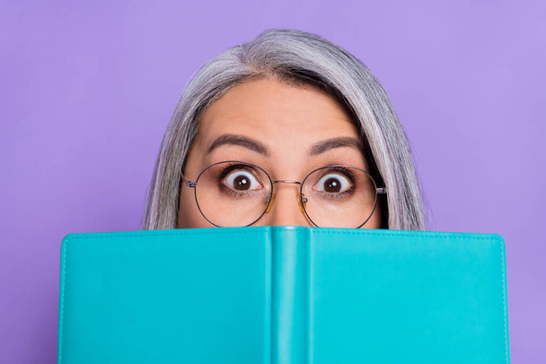 Фото умно шокированной пенсионерки носить свитер очки книжные покрытия лицо изолированный фиолетовый цвет фона. - Фото, изображение