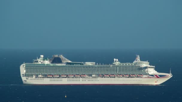 Een cruiseschip met de Britse vlag op een zonnige dag tegen de blauwe lucht beweegt zich naar de open zee, zijaanzicht - Video