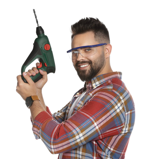 Young man in protective goggles with power drill on white background - Fotó, kép