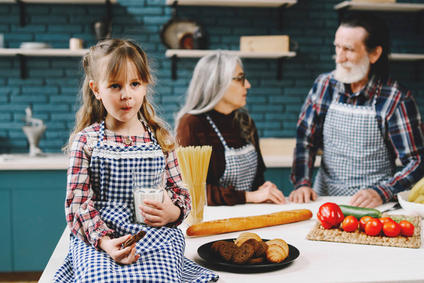 Happy seniors and their grandaughter cooking in kitchen. Child having a meal. - Foto, Bild