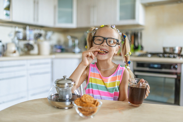 Κοριτσάκι που τρώει μπισκότα και πίνοντας τσάι - Φωτογραφία, εικόνα