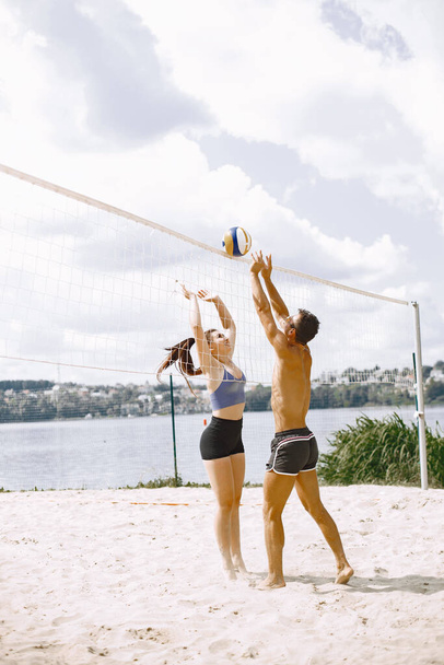 Sports and active life theme. Young players play volleyball. Beach playground. - Foto, Bild