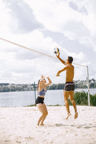 Sports and active life theme. Young players play volleyball. Beach playground. - Fotó, kép