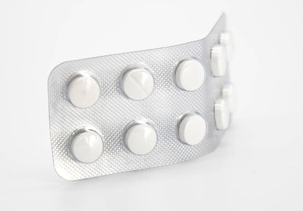 píldoras blancas redondas en hojas de embalaje sobre fondo blanco, primer plano, medicina, tableta - Foto, imagen