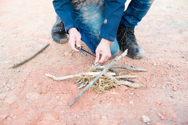Starting a fire with a firesteel, survival and adventure equipment, outdoor skill, man making a campfire - Foto, Imagen