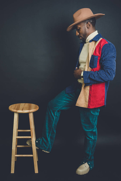 A vertical studio shot of an African American male model posing in colorful fashionable clothes - Foto, Imagen