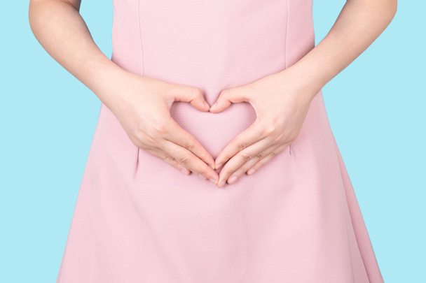 Gros plan de femme en bonne santé fait main en forme de coeur sur son estomac. Concept de bon digestif, intestin sain, probiotiques, forme mince, gynécologie et soins de santé pour les femmes. - Photo, image