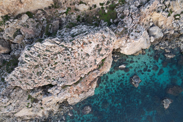 Mavi bir okyanus ve gün ışığında kayalık bir uçurum manzarası. - Fotoğraf, Görsel