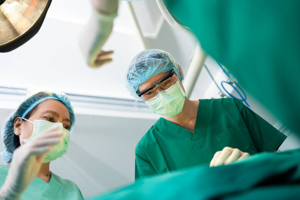 Low Angle Shot of Professional surgeons team performing surgery in operating room, surgeon, Assistants, and Nurses Performing Surgery on a Patient, health care cancer and disease treatment concept - Photo, Image