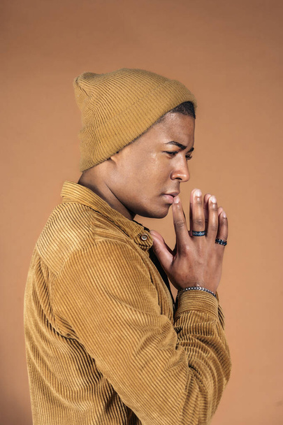 Young man wearing casual clothes posing in studio shot against brown background. - Foto, Imagem