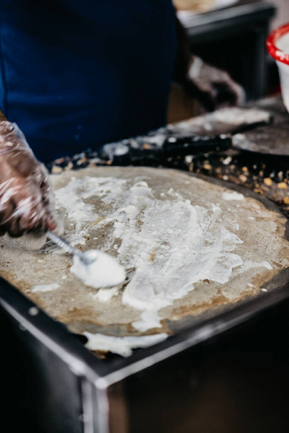 A closeup shot of adult male hands cooking crepe in the kitchen with blurred background - Foto, Bild