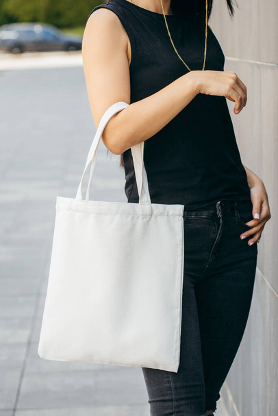 Sokaktaki genç Asyalı manken kız elinde beyaz bir çanta tutuyor. - Fotoğraf, Görsel