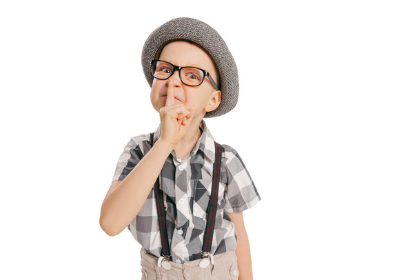 Secrets. Portrait of cute little boy, happy kid in eyeglasses and hat isolated on white studio background with copyspace for ad. Concept of child emotions, facial expression, beauty and ad. - Φωτογραφία, εικόνα