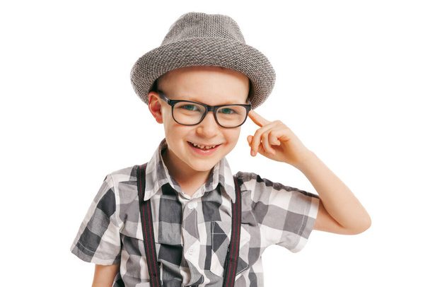 Looking at camera. Portrait of cute little boy, happy kid in eyeglasses and hat isolated on white studio background with copyspace for ad. Concept of child emotions, facial expression, beauty and ad. - Fotó, kép