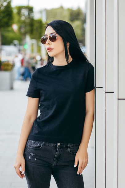Stylish brunette asian girl wearing black t-shirt posing against street , urban clothing style. Street photography - Foto, Imagem