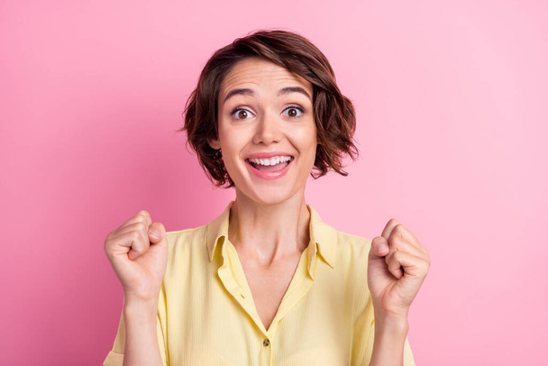 Photo of hooray young brunette lady hands fists wear yellow t-shirt isolated on pink color background. - Φωτογραφία, εικόνα