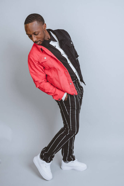 A vertical studio shot of an African American male model posing in colorful fashionable clothes - Foto, Bild