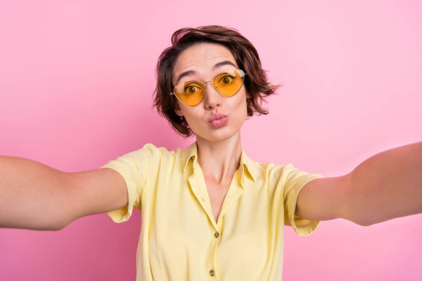 Photo of cute young brunette lady do selfie wear yellow t-shirt eyewear isolated on pink color background. - Valokuva, kuva