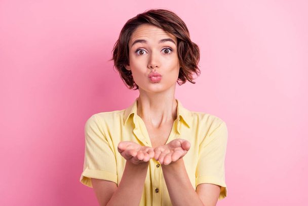 Photo of cute millennial brunette lady blow kiss wear yellow t-shirt isolated on pink color background. - Zdjęcie, obraz