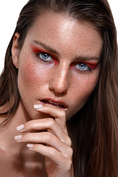 A studio shot of Caucasian woman with brunette hair and freckles on face posing with finger on lips - 写真・画像