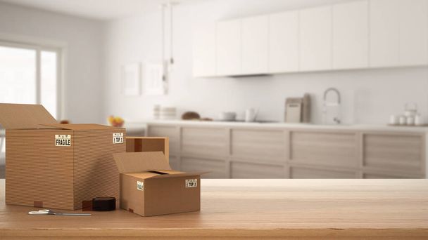 Wooden table, desk or shelf with stack of cardboard boxes over blurred view of scandinavian kitchen with appliances, modern interior design, moving house concept with copy space - Φωτογραφία, εικόνα