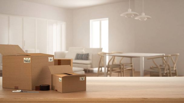 Wooden table, desk or shelf with stack of cardboard boxes over blurred view of dining and living room with soda and table, modern interior design, moving house concept with copy space - Photo, Image