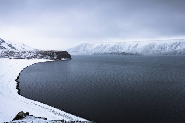 A chilling view of the frozen lake of Kleifarvatn in Iceland under a cloudy sky - Фото, зображення