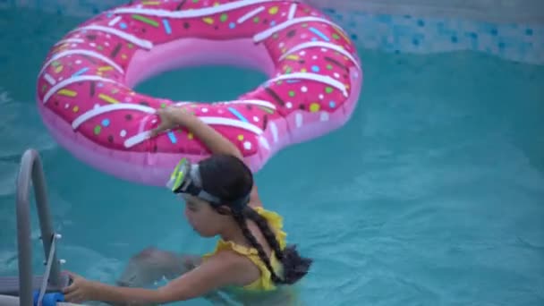 meisje speelt een opblaasbare ring is in het zwembad in de tuin. - Video