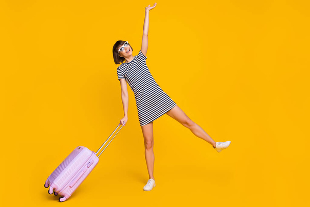 Full size photo of funny brunette millennial lady with bag wear dress spectacles sneakers isolated on yellow background. - 写真・画像