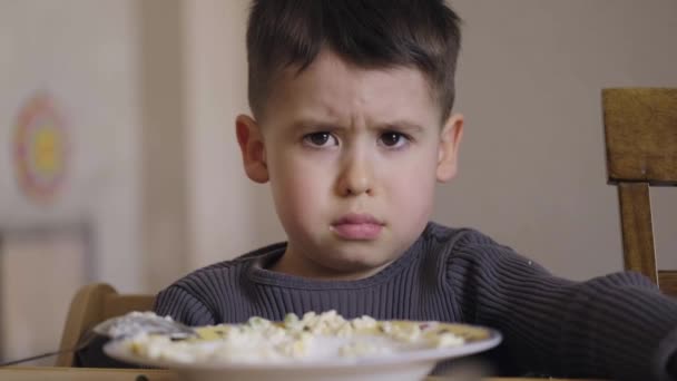 Kaukasischer Junge, der sich weigert, sein Frühstück zu essen, sitzt morgens am Tisch. Gesundes Frühstück. Gesundes Essen. Gesunde Ernährung. - Filmmaterial, Video